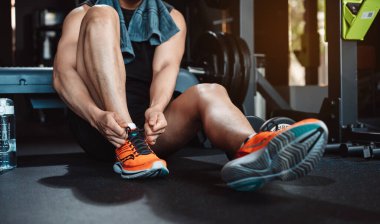 Spor salonunda egzersiz yapmak, spor yaptıktan sonra dambıl ve su şişesiyle dinlenmek sağlıklı bir vücut geliştirme..
