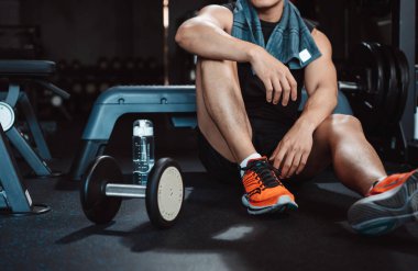 Spor salonunda egzersiz yapmak, spor yaptıktan sonra dambıl ve su şişesiyle dinlenmek sağlıklı bir vücut geliştirme..