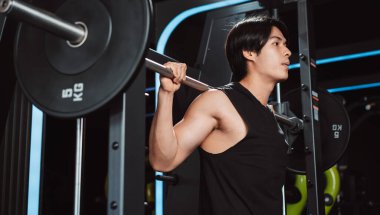 Spor salonunda ağırlık kaldıran vücut geliştirici bir adam. Vücut geliştirici halterle egzersiz yapıyor. Spor eğitimi, sağlıklı vücut geliştirme, sporcu kaslı yaşam tarzı..