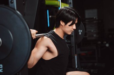 Spor salonunda ağırlık kaldıran vücut geliştirici bir adam. Vücut geliştirici halterle egzersiz yapıyor. Spor eğitimi, sağlıklı vücut geliştirme, sporcu kaslı yaşam tarzı..