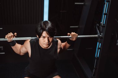 Spor salonunda ağırlık kaldıran vücut geliştirici bir adam. Vücut geliştirici halterle egzersiz yapıyor. Spor eğitimi, sağlıklı vücut geliştirme, sporcu kaslı yaşam tarzı..