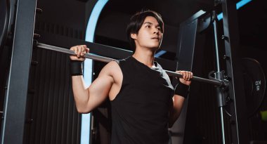 Spor salonunda ağırlık kaldıran vücut geliştirici bir adam. Vücut geliştirici halterle egzersiz yapıyor. Spor eğitimi, sağlıklı vücut geliştirme, sporcu kaslı yaşam tarzı..