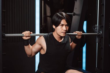 Spor salonunda ağırlık kaldıran vücut geliştirici bir adam. Vücut geliştirici halterle egzersiz yapıyor. Spor eğitimi, sağlıklı vücut geliştirme, sporcu kaslı yaşam tarzı..