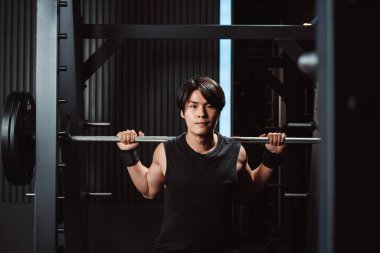 Spor salonunda ağırlık kaldıran vücut geliştirici bir adam. Vücut geliştirici halterle egzersiz yapıyor. Spor eğitimi, sağlıklı vücut geliştirme, sporcu kaslı yaşam tarzı..