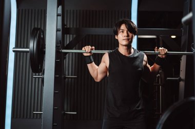 Spor salonunda ağırlık kaldıran vücut geliştirici bir adam. Vücut geliştirici halterle egzersiz yapıyor. Spor eğitimi, sağlıklı vücut geliştirme, sporcu kaslı yaşam tarzı..