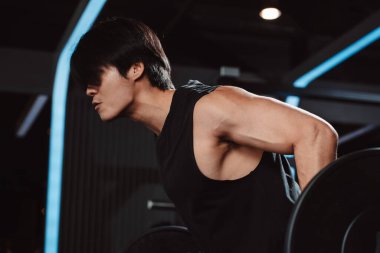 Spor salonunda halterle vücut geliştiren bir erkek. Halterle egzersiz yapan bir vücut geliştirici. Spor eğitimi, sağlıklı vücut geliştirme, sporcu kaslı yaşam tarzı..