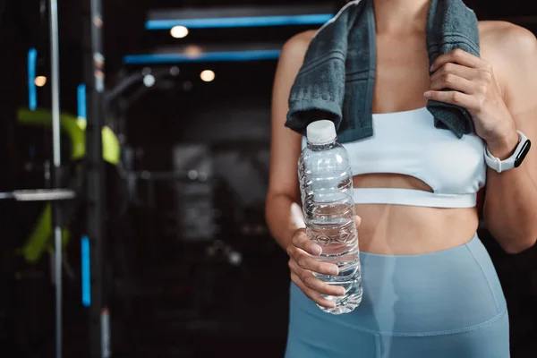 Woman drinking water recovery health exercise workout in gym fitness breaking relax after training sport with kettlebell, dumbbells and water bottle healthy lifestyle bodybuilding.