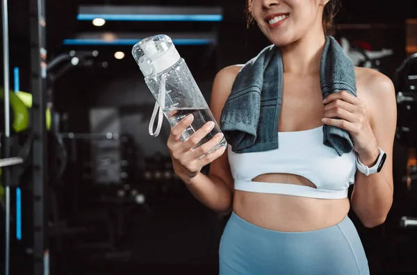Woman drinking water recovery health exercise workout in gym fitness breaking relax after training sport with kettlebell, dumbbells and water bottle healthy lifestyle bodybuilding.