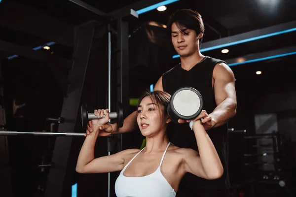 Woman working out Bodybuilder with coaching assistance to support weights at the gym. bodybuilder doing exercises with barbell. training sport healthy lifestyle bodybuilding.