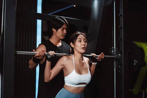 stock image Woman working out Bodybuilder with coaching assistance to support weights at the gym. bodybuilder doing exercises with barbell. training sport healthy lifestyle bodybuilding.