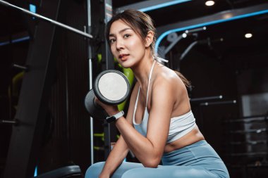 Vücut geliştiren kadın spor salonunda halterli ağırlık çalışıyor. Vücut geliştirici halterle egzersiz yapıyor. Spor eğitimi, sağlıklı vücut geliştirme, sporcu kaslı yaşam tarzı..