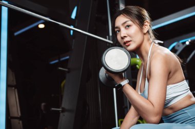 Vücut geliştiren kadın spor salonunda halterli ağırlık çalışıyor. Vücut geliştirici halterle egzersiz yapıyor. Spor eğitimi, sağlıklı vücut geliştirme, sporcu kaslı yaşam tarzı..