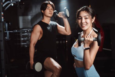 Sporcu ve kadın sporcuların spor eğitiminden sonra spor salonunda egzersiz yapıp spor yaptıktan sonra halterlerle spor yaptıktan sonra sağlıklı bir vücut geliştirme..