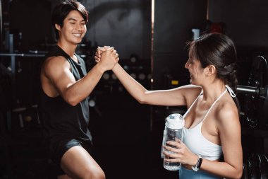 Sporcu ve kadın sporcuların spor eğitiminden sonra spor salonunda egzersiz yapıp spor yaptıktan sonra halterlerle spor yaptıktan sonra sağlıklı bir vücut geliştirme..