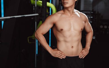 Sporcu spor salonunda spor yaptıktan sonra ayakta duruyor. Dambıllarla spor yapıyor. Sağlıklı vücut geliştirme..