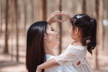 Mutlu aile, anne, tatlı kız ormanda çimen tarlasında aşk duygusunun tadını çıkarıyor..