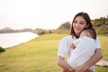 Annelik ve yeni doğan doğum hayatı. Anne ve bebek gün batımında oynuyorlar, aile birlikte eğleniyor. çocuk bakımı, annelik kavramı.