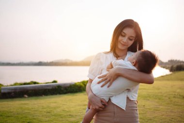 Annelik ve yeni doğan doğum hayatı. Anne ve bebek gün batımında oynuyorlar, aile birlikte eğleniyor. çocuk bakımı, annelik kavramı.