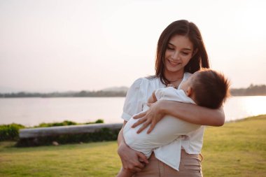 Annelik ve yeni doğan doğum hayatı. Anne ve bebek gün batımında oynuyorlar, aile birlikte eğleniyor. çocuk bakımı, annelik kavramı.