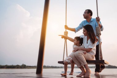 Mutlu aile gün batımında parkta salıncakla eğleniyor doğada, aile hayatının hafta sonu aktiviteleri..