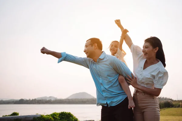 stock image Happy family in the park sunset light. family on weekend running together in the meadow with river Parents hold the child hands.health life insurance plan concept.