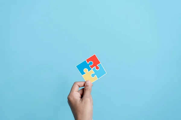 stock image Hand holding Color puzzle symbol of awareness for autism spectrum disorder family support. Father, Mother, Children holding jigsaw puzzle Autism World Awareness Day.