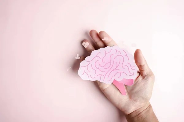 Hand holding human brain icon paper cut, idea creative intelligence thinking or Awareness dementia, stroke, seizure or mental health. Neurology and Psychology care.