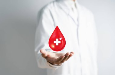 Beyaz önlüklü doktor kan bağışı, kan nakli, dünya kan bağışı günü, kan vermek için kızıl haç alıyor. Dünya hemofili günü konsepti..