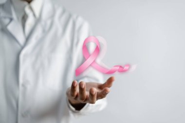 Doktor elinde sanal pembe kurdele kanseri, göğüs kanseri farkındalığı ve sağlık kontrolü konsepti tutuyor..