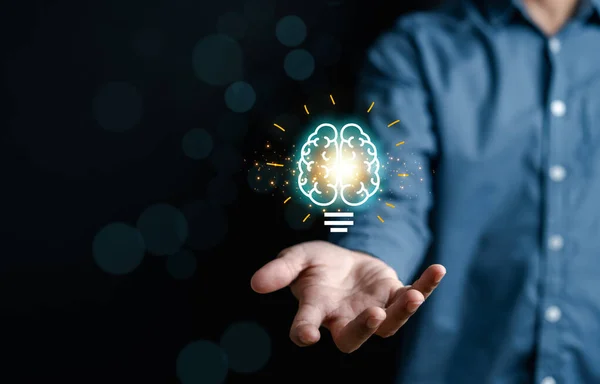 Stock image Businessman holding virtual lightbulb with brain icon, idea, innovation and inspiration with glowing virtual brain, smart intelligent creativity with bulbs, Motivation and innovation concept