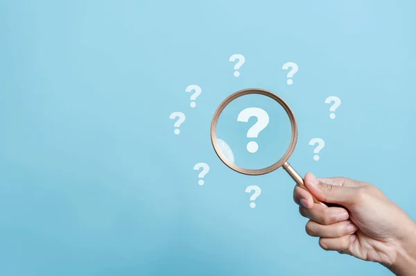 stock image Hand holding Magnifier Question icon inside and many question thinking idea creative concept.