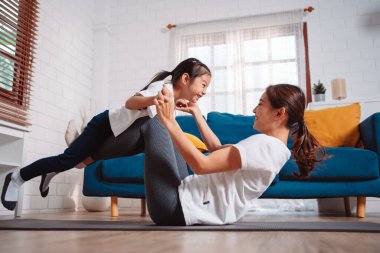 Anne ve kızı evde mutlu bir şekilde egzersiz yapıyorlar. Esneklik için kas gücü oluşturmak için, spor antrenmanı için aile kavramı oluşturmak için..