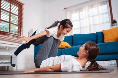 Anne ve kızı evde mutlu bir şekilde egzersiz yapıyorlar. Esneklik için kas gücü oluşturmak için, spor antrenmanı için aile kavramı oluşturmak için..