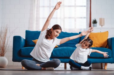 Anne ve kızı evde mutlu bir şekilde egzersiz yapıyorlar. Esneklik için kas gücü oluşturmak için, spor antrenmanı için aile kavramı oluşturmak için..