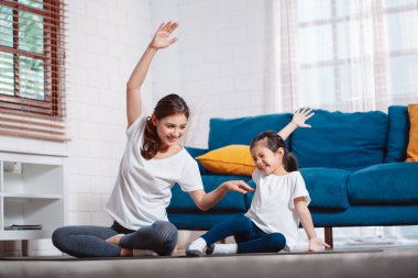 Anne ve kızı evde mutlu bir şekilde egzersiz yapıyorlar. Esneklik için kas gücü oluşturmak için, spor antrenmanı için aile kavramı oluşturmak için..