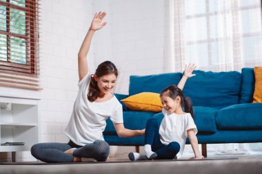 Anne ve kızı evde mutlu bir şekilde egzersiz yapıyorlar. Esneklik için kas gücü oluşturmak için, spor antrenmanı için aile kavramı oluşturmak için..
