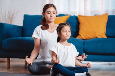 Anne ve kızı evde mutlu bir şekilde egzersiz yapıyorlar. Esneklik için kas gücü oluşturmak için, spor antrenmanı için aile kavramı oluşturmak için..