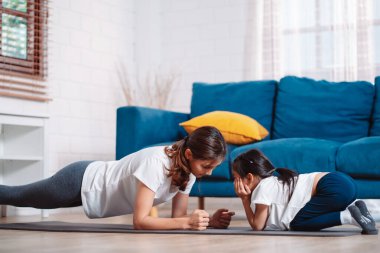 Anne ve kızı evde mutlu bir şekilde egzersiz yapıyorlar. Esneklik için kas gücü oluşturmak için, spor antrenmanı için aile kavramı oluşturmak için..