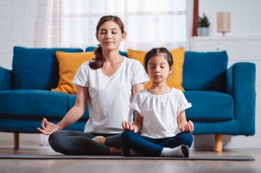 Anne ve kızı evde mutlu bir şekilde egzersiz yapıyorlar. Esneklik için kas gücü oluşturmak için, spor antrenmanı için aile kavramı oluşturmak için..