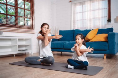 Anne ve kızı evde mutlu bir şekilde egzersiz yapıyorlar. Esneklik için kas gücü oluşturmak için, spor antrenmanı için aile kavramı oluşturmak için..