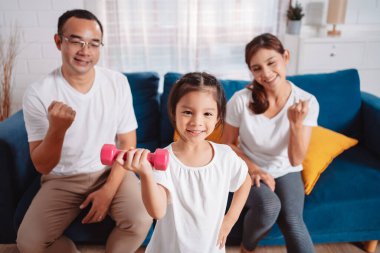 Ebeveynler ve kızlarından oluşan aile evde mutlu bir şekilde egzersiz yapıyor. Esneklik için, kas gücü geliştirmek için, Spor Antrenmanı ailesini birlikte çalıştırmak için..