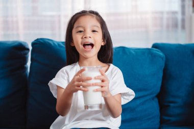 Evde beslenme vitamini için süt içen tatlı Asyalı kız sağlıklı ve güçlü dişler..