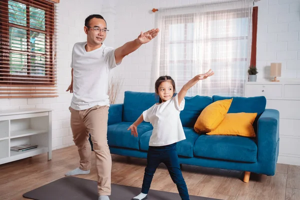 Baba ve kızı evde mutlu bir şekilde egzersiz yapıyorlar. Esneklik için kas gücü oluşturmak için, spor antrenmanı için aile kavramı oluşturmak için..