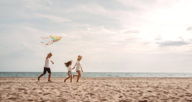 Mutlu Asyalı aile deniz sahilinin tadını çıkarıyor. Baba, anne ve kız, yaz tatilinde okyanus sahilinde plaj oynarken eğleniyorlar. Tatil hayatı konsepti olan mutlu bir aile..