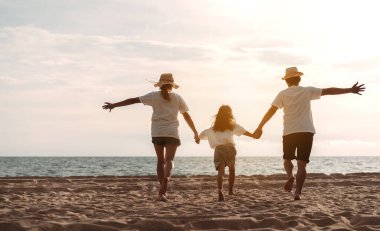 Mutlu Asyalı aile deniz sahilinin tadını çıkarıyor. Baba, anne ve kız, yaz tatilinde okyanus sahilinde plaj oynarken eğleniyorlar. Tatil hayatı konsepti olan mutlu bir aile..