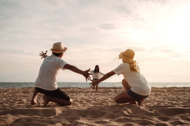 Mutlu Asyalı aile deniz sahilinin tadını çıkarıyor. Baba, anne ve kız, yaz tatilinde okyanus sahilinde plaj oynarken eğleniyorlar. Tatil hayatı konsepti olan mutlu bir aile..