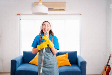 Happy Housework ya da ev hizmetçisi kadın şarkı söyleyip tozları temizliyor, küçük işletmeleri temizliyor. profesyonel ekipman eski evi temizliyor.