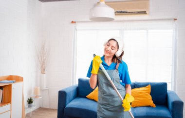 Happy Housework ya da ev hizmetçisi kadın şarkı söyleyip tozları temizliyor, küçük işletmeleri temizliyor. profesyonel ekipman eski evi temizliyor.