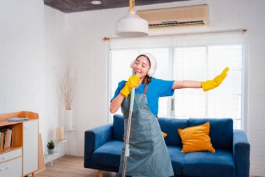 Happy Housework ya da ev hizmetçisi kadın şarkı söyleyip tozları temizliyor, küçük işletmeleri temizliyor. profesyonel ekipman eski evi temizliyor.