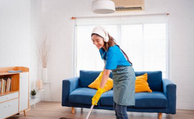 Happy Housework ya da ev hizmetçisi kadın şarkı söyleyip tozları temizliyor, küçük işletmeleri temizliyor. profesyonel ekipman eski evi temizliyor.